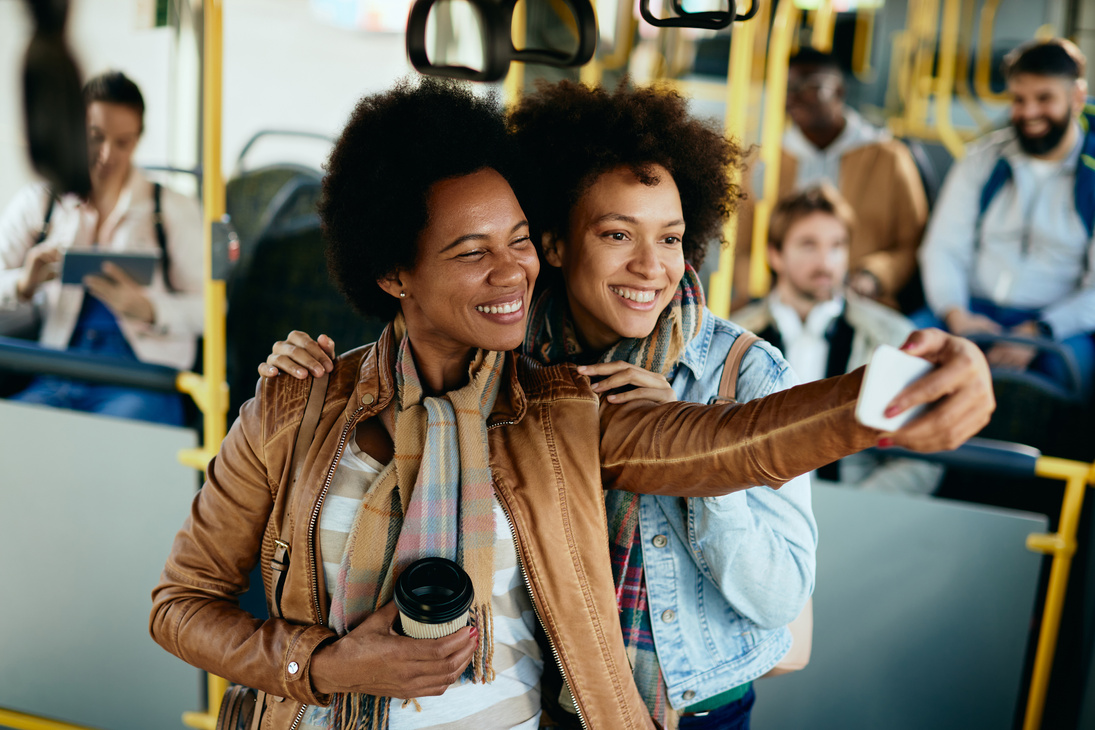 Happy black women having fun while taking selfie in a bus.